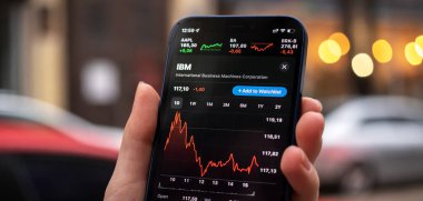 Kharkov, Ukrayna - 1 Aralık 2021: IBM hisse senedi ticareti, pankart. Finansal grafikler, yatırım, dijital bankacılık konsepti. Elinde borsa uygulaması olan akıllı telefon. 