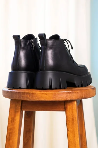Zbliżenie tylnej strony czarnych eleganckich butów na drewnianym tle. Skórzane buty zimowe, stylowa koncepcja obuwia damskiego — Zdjęcie stockowe