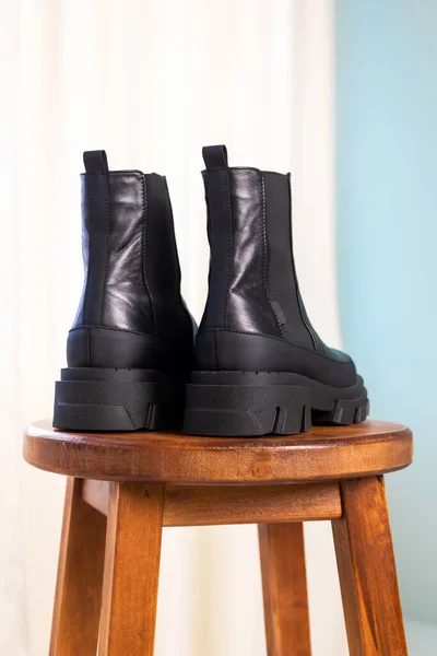 Zbliżenie tylnej strony czarnych eleganckich butów na drewnianym tle. Skórzane buty zimowe, stylowa koncepcja obuwia damskiego — Zdjęcie stockowe