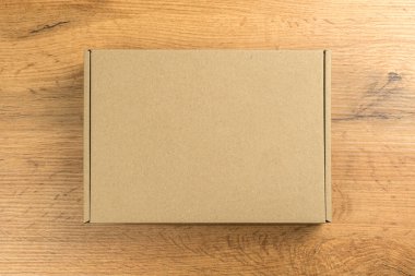 Ahşap masa arkasında kahverengi karton kutu. Model fotoğraf, teslimat konsepti ve ürünlerinizi ve mallarınızı gönderme vs..