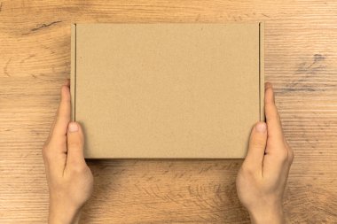 Karton kutu modeli olan teslimatçı, üst manzara. Ahşap masa arka planı. Yiyecek, kozmetik ya da tıbbi ambalaj için uygun. Sevkiyat ve teslimat konsepti fotoğrafı