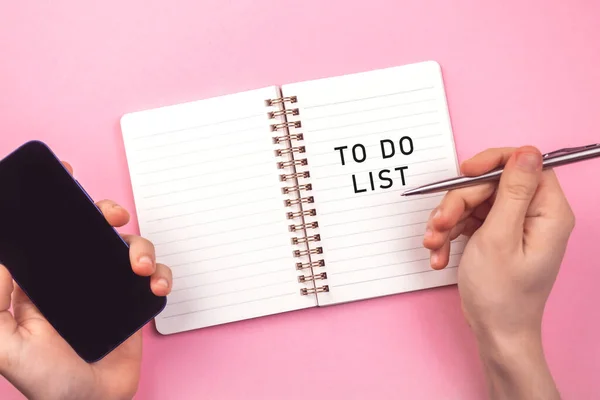 新年のリストを行うには空です ピンクのテーブルのノート 企画コンセプトの背景 スマートフォンやペンで手 トップ表示 — ストック写真
