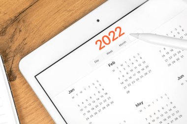 2022 takvimi yakın plan, tablet bilgisayar ekranı. İş ahşap masa üstü arkaplanı. Planlama atama ve buluşma kavramı