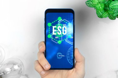 ESG konsepti. Sürdürülebilir ve etik sektörde çevre, sosyal ve yönetim. Mermer masada modern akıllı telefon. Yeşil enerji, ekoloji bakımı 