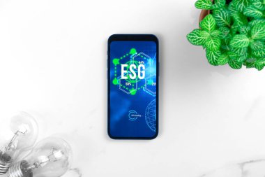 ESG konsepti. Sürdürülebilir ve etik sektörde çevre, sosyal ve yönetim. Mermer masada modern akıllı telefon. Yeşil enerji, ekoloji bakımı 