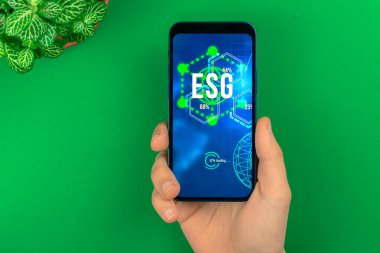 ESG konsepti. Sürdürülebilir ve etik sektörde çevre, sosyal ve yönetim. Modern akıllı telefon masada. Yeşil enerji, ekoloji bakımı