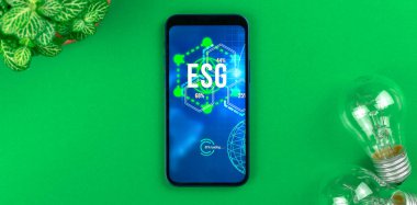 ESG konsept pankartı. Sürdürülebilir ve etik sektörde çevre, sosyal ve yönetim. Modern akıllı telefon masada. Yeşil enerji, ekoloji bakımı