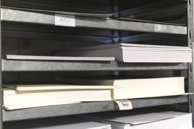 Matbaa deposu ve kağıt kaplı metal raf. Çalışma süreci, baskı endüstrisi konsepti fotoğrafı