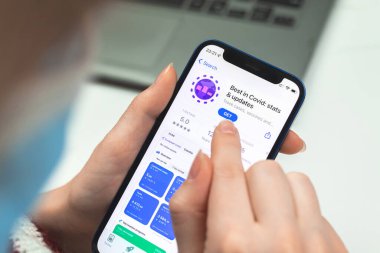 Kharkov, Ukraine - January 10, 2022: COVID-19 stats app icon closeup. Woman uses the application on Apple iPhone 12