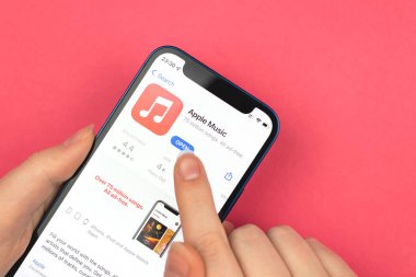 Kharkov, Ukraine - January 10, 2022: Apple Music app icon closeup. Woman uses the application on Apple iPhone 12 mini