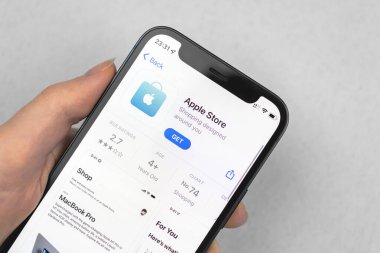 Kharkov, Ukraine - January 10, 2022: Apple Store app icon close-up. Woman uses the application on Apple iPhone 12 mini
