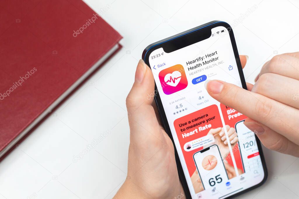 Kharkov, Ukraine - January 10, 2022: Heartify app icon closeup. Woman uses the application on Apple iPhone 12