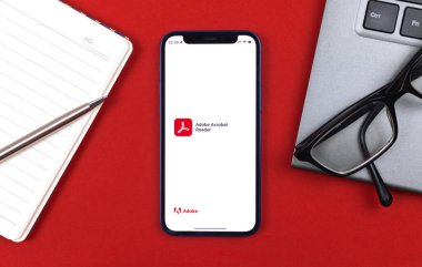 Kharkov, Ukraine - January 10, 2022: Adobe Acrobat Reader application logo. Business desktop background, top view