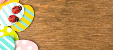 Colorful Easter eggs banner border, old rustic wood background, flat lay design, top view with copy space