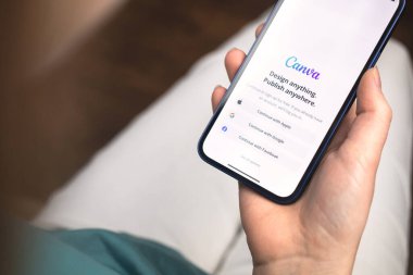 Kharkov, Ukrayna - 10 Ocak 2022: Kadın Canva uygulaması kullanıyor. Apple iPhone 12 ile el, logolu cep telefonu ekranı