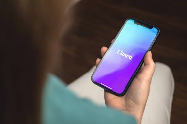 Kharkov, Ukrayna - 10 Ocak 2022: Kadın Canva uygulaması kullanıyor. Apple iPhone ile el, logolu cep telefonu ekranı