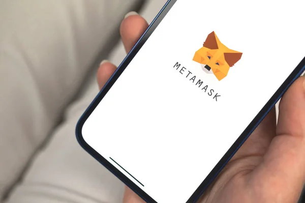 Kharkov, Ukrayna - 10 Ocak 2022: Kadın Metamaske NFT uygulaması kullanıyor. Apple iPhone 12 ile el, logolu cep telefonu ekranı