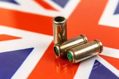 Birleşik Krallık bayrağı üzerinde silah mermileri. Suç, suç ve yolsuzluk kavramı. Birleşik Krallık kanun kaçağı, sosyal sorun ve silahlı saldırı geçmişi