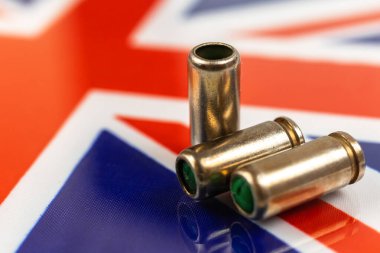 Birleşik Krallık bayrağı üzerinde silah mermileri. Suç, suç ve yolsuzluk kavramı. Birleşik Krallık kanun kaçağı, sosyal sorun ve silahlı saldırı geçmişi