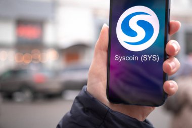Kharkov, Ukrayna - 2 Şubat 2022: Syscoin para sembolü. Şifreli para ticareti, dijital ve sanal para, mobil bankacılık. Akıllı telefon ile el, kripto simgesi ile ekran yakın çekim