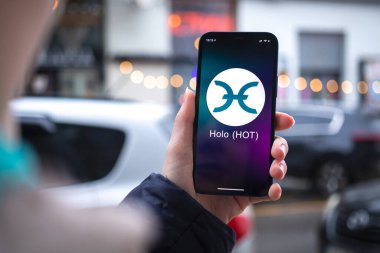 Kharkov, Ukrayna - 2 Şubat 2022: HOLO sıcak para sembolü. Şifreli para ticareti, dijital ve sanal para, mobil bankacılık. Akıllı telefon ile el, kripto simgesi ile ekran yakın çekim