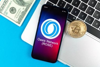 Kharkov, Ukrayna - 31 Ocak 2022: Oasis Network ROSE para sembolü. Şifreli para ticareti, dijital ve sanal para, cep telefonu konsepti ile bankacılık. Çalışma alanı, dizüstü bilgisayarlı masa