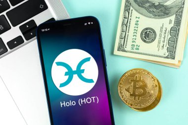 HOLO sıcak para sembolü. Şifreli para ticareti, dijital ve sanal para, cep telefonu konsepti ile bankacılık. Çalışma alanı, dizüstü bilgisayarlı fotoğraf tablosu