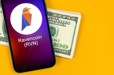 Ravencoin RVN sembolü. Şifreli para ticareti, dijital ve sanal para, cep telefonu konsepti ile bankacılık. Çalışma alanı, masa üstü fotoğrafı.