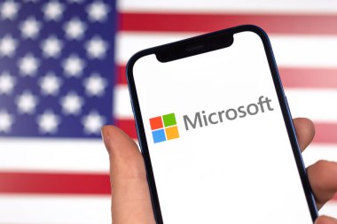 ABD bayraklı Microsoft Amerikan şirketinin logosu. Cep telefonunun yakın plan fotoğrafı olan el.
