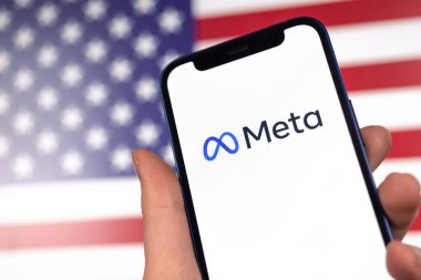 ABD bayraklı arka planda meta logosu. Amerikan şirketi. Cep telefonunun yakın plan fotoğrafı olan el.