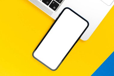 Üst görünüm modeli. Beyaz ekranlı akıllı telefon, dizüstü bilgisayarlı düz sarı arka plan. Asgari çalışma alanı, modern dizüstü bilgisayar, kopyalama alanı 