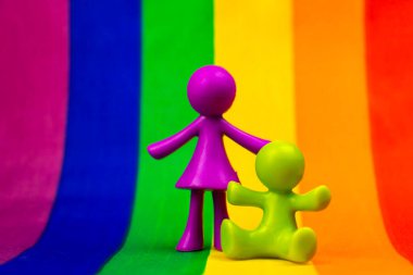 LGBT aile kavramı. Gökkuşağı arka planında çocuk heykelcikler. Homoseksüel ve lezbiyen topluluğu