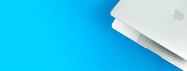 Apple Macbook Air ve parlak mavi masa arkaplanı M1. İş ve ofis konsepti, üst görünüm, düz yatak