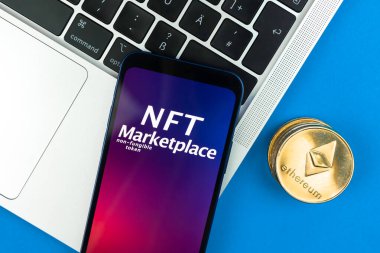 NFT kripto pazar yeri konsepti. Finanse edilemeyen jetonla çalışmak için cep telefonu. Kripto parasının geleceği, engelleme teknolojisi. Laptop ve ethereum madeni para ile ofis masası, üst görünüm