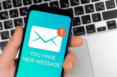Yeni mesaj simgesi ve bildirim içeren cep telefonu kullanan bir adam. İş iletişimi ve internet kavramı, dizüstü bilgisayar klavye geçmişi