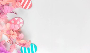 Renkli paskalya yumurtaları ve çiçekler. Pembe bahar çiçekleriyle sınır tasarımı. Mutlu Paskalya kutlamaları konsepti, fotokopi alanı, düzlük, üst görünümü olan tatil dekorasyonu