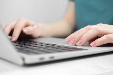 Laptop beyaz masada ve genç kadın eli klavyede. Serbest iş yeri, ev kavramından çalışma