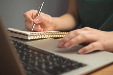 Laptop ahşap masada ve genç kadın eli klavyede. Serbest iş yeri, ev kavramından çalışma