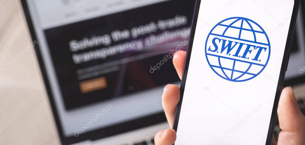Kharkov, Ukraine - February 27, 2022: SWIFT logo close-up on mobile phone screen. Woman use S.W.I.F.T. banking and international technology concept photo