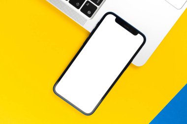 Apple iPhone model ekran, dizüstü bilgisayarlı düz masa, sarı arka plan. Asgari tasarım, cep telefonu modeli, üst görünüm, kopyalama alanı 