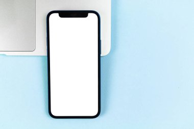 Apple iPhone 'un düz ekran modeli, dizüstü bilgisayarlı ofis masaüstü, parlak mavi arkaplan. Üst görünüm, uzay fotoğrafını kopyala