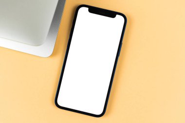 Apple iPhone maketi düz yatıyordu, bilgisayarlı ofis masaüstü, parlak bej arka plan. Üst görünüm, uzay fotoğrafını kopyala