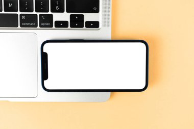Apple iPhone yatay olarak tasarlanmış, dizüstü bilgisayarı ve bej arka planı olan bir ofis bilgisayarı. Üst görünüm, uzay fotoğrafını kopyala
