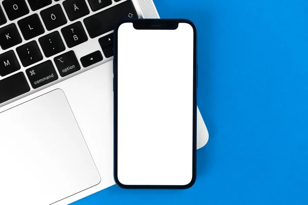 Tela de maquete do iPhone da Apple, mesa de escritório plana com laptop, fundo azul. Design mínimo, mockup de telefone móvel, vista superior, espaço de cópia — Fotografia de Stock