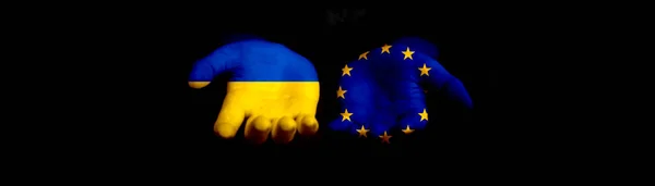 Europe union and Ukraine flags and hands on black background, banner. Europe and Ukraine, NATO. Conflict, protest and russian invasion, war concept