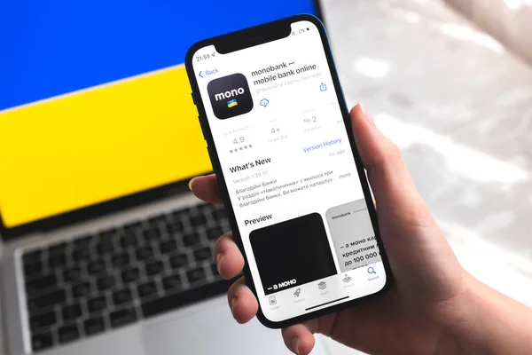 Poltava, Ukrayna - 7 Nisan 2022: Monobank mobil bankacılık uygulaması Ukrayna 'da. Akıllı telefonlu el, ekranda logo. Ulusal bayrak fotoğraflı arkaplan