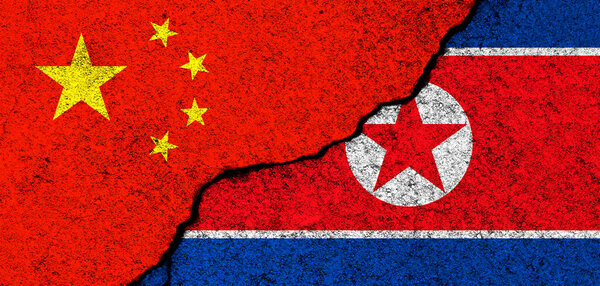 China and North Korea. Flags background. Concept of politics, economy, culture and conflicts, war. Friendships and cooperation. Painted on concrete walls banner