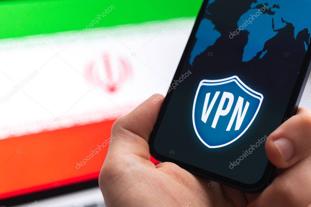 VPN in Iran. Secure and safe internet concept. Privacy. Hand with mobile phone and VPN application. Flag and laptop on the background photo