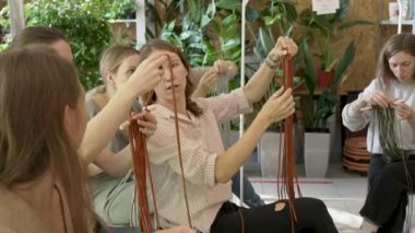 Sanat dersine katılan bir grup kadın. Bayan öğrenciler ve öğretmen birlikte atölyede Boho stilinde ev dekorasyonu yapıyorlar. Sanat okulu stüdyosunda el yapımı makrome örüyor. Yaratıcılık, insanların eğitimi