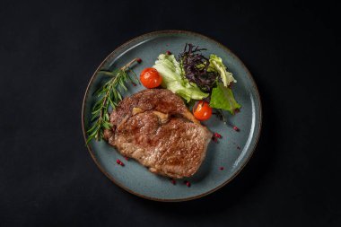 Siyah arka planda baharat, sebze ve sebzeli orta pişmiş biftek. Restoranda arkadaşlarla güzel bir akşam yemeği. Boşluğu kopyala